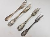 four forks and two spoons sitting on a white surface