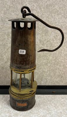 une vieille lanterne en métal et en verre est posée sur une surface blanche