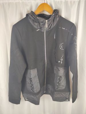 veste à capuche avec fermetures éclair et poches, suspendue à un cintre devant un rideau blanc