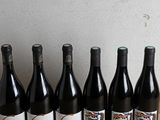 six bottles of wine are lined up on a wooden table