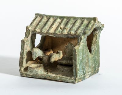 une petite figurine représentant une crèche avec un chien à l'intérieur