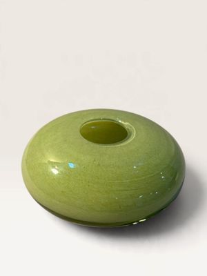 a green vase that is sitting on a white surface