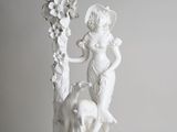 une statue blanche représentant une femme et un chien, posée sur un socle