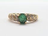 an image of a ring with a green stone surrounded by diamonds