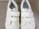 pair of white shoes with velcro straps on a beige surface