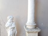 une statue représentant un garçon tenant un bébé dans ses bras, à côté d'un pilier