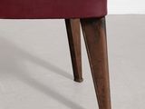 a red leather bench with wooden legs in a white room