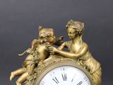 a gold clock with a statue of two cherensils on top of it