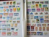 un livre ouvert, sur lequel sont collés des timbres et dans lequel se trouve un stylo