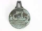 a metal object with a ship on it on a white surface