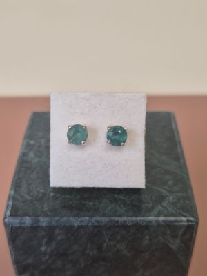 a pair of green stone stud earrings sitting on top of a box