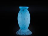 un vase en verre bleu posé sur une surface noire