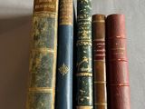 quatre vieux livres alignés les uns à côté des autres sur une surface blanche