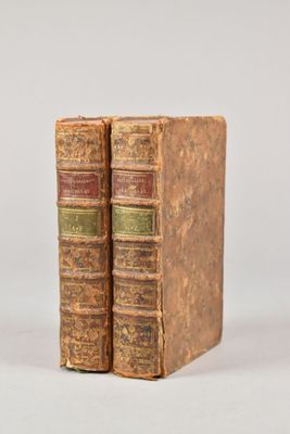 two old books sitting on top of each other on a white surface