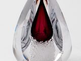 a red tear shaped glass object on a white surface