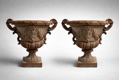 une paire d'urnes en pierre sculptées posées sur des socles, sur fond blanc