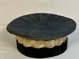 un chapeau noir et doré posé sur une table blanche