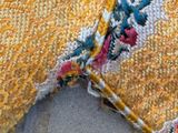 a close up of a yellow and red rug on the ground