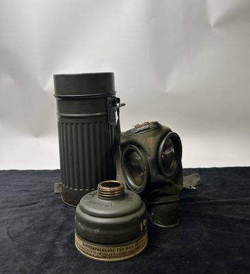 an old gas mask and a canister on a black cloth