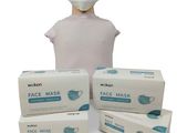 a person wearing a face mask and three boxes of face masks