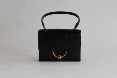 un sac à main noir avec une poignée dorée sur fond blanc