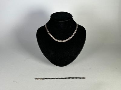 un collier à chaîne en argent exposé à côté d'un mannequin noir