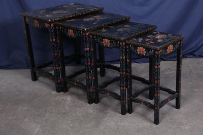 trois tables gigognes noires et rouges posées sur un sol en béton