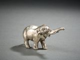 a silver elephant figurine on a gray surface
