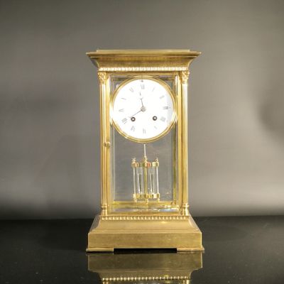 une horloge dorée posée sur une table noire, sur fond gris