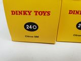 two boxes of dinky toys sitting on top of a white table
