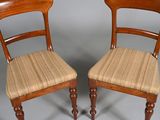 pair of antique wooden chairs with upholstered seat cushions