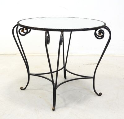 an iron table with a glass top on a white floor