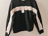 un pull noir et blanc suspendu à un cintre accroché au mur