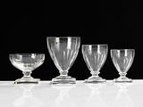 four wine glasses lined up on a white table