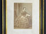 une vieille photo représentant une femme en robe, assise sur une chaise