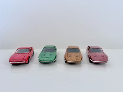 quatre petites voitures sont alignées sur une surface blanche