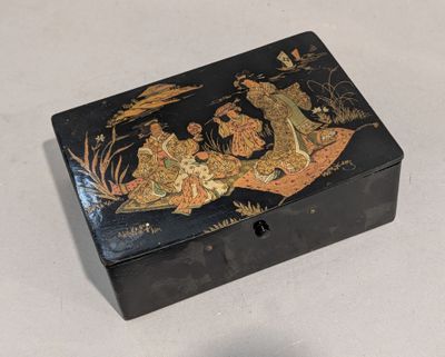 une boîte noire ornée d'une peinture, posée sur une table