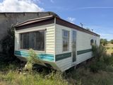 a trailer that is sitting in the grass near a building