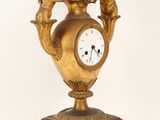a gold clock with angels on it on a stand