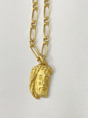 a close up of a gold necklace with a jesus head on it