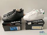 two pairs of black and white adidas sneakers sitting on top of a box