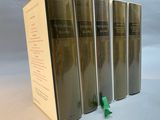 four books are lined up in a row on a white surface