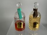 two bottles of perfume sitting on a clear table
