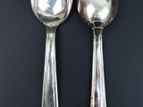 pair of silver spoons on a black surface with a black background