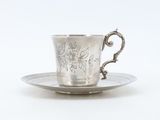 a silver cup and saucer sitting on a saucer