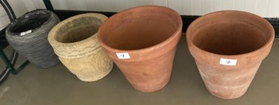 trois grands pots en argile posés les uns à côté des autres sur le sol