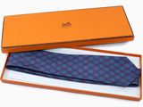 une cravate orange et bleue dans un coffret cadeau, posée sur un fond blanc