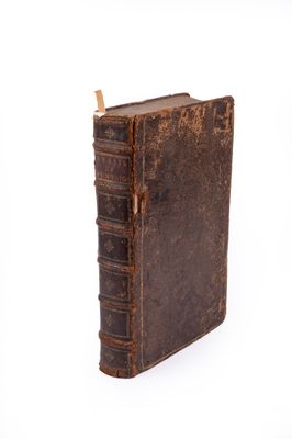 an old book is sitting on top of a white surface