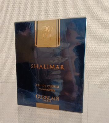 Le flacon de parfum Shalimar est posé sur la table.