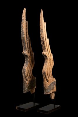 une paire de sculptures en bois sculpté posées sur des socles, sur fond noir